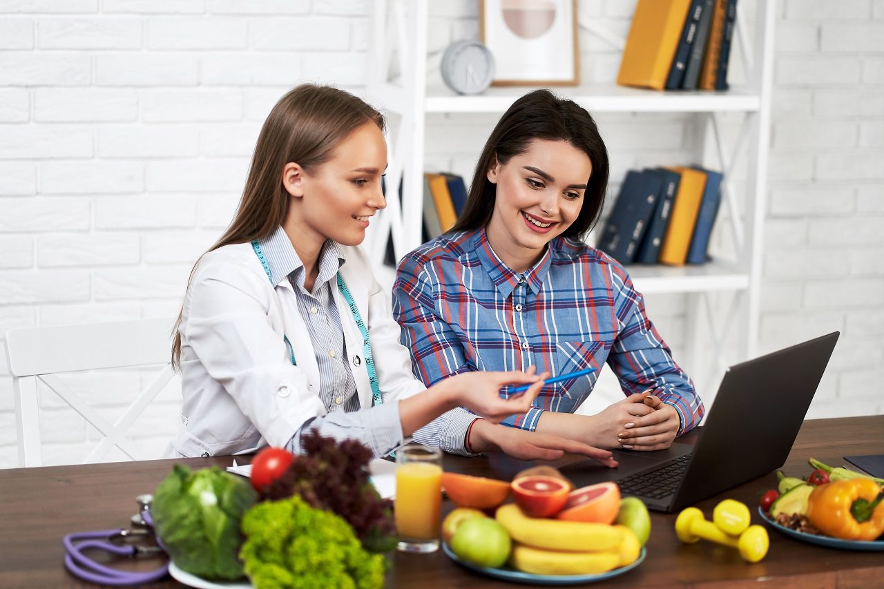 A smiling nutritionist advises a young patient woman on proper n