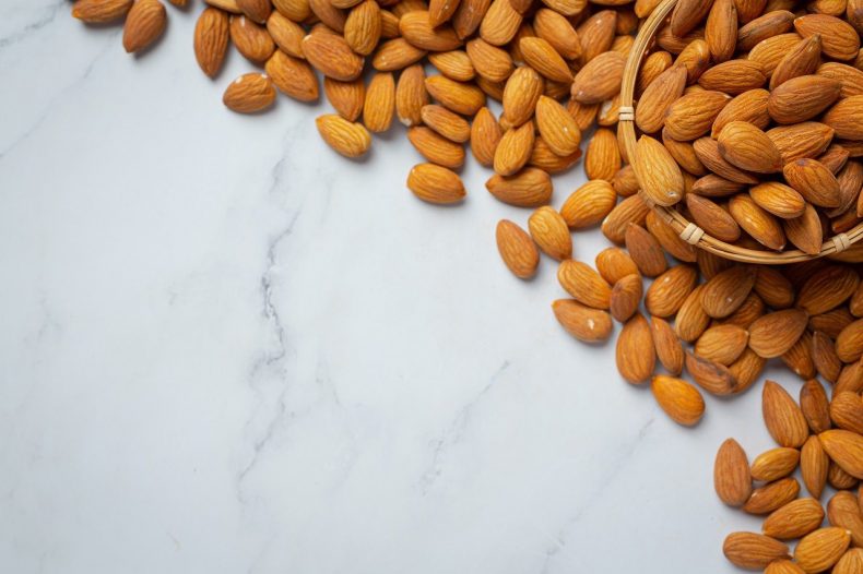 Almonds in bowl on marble background